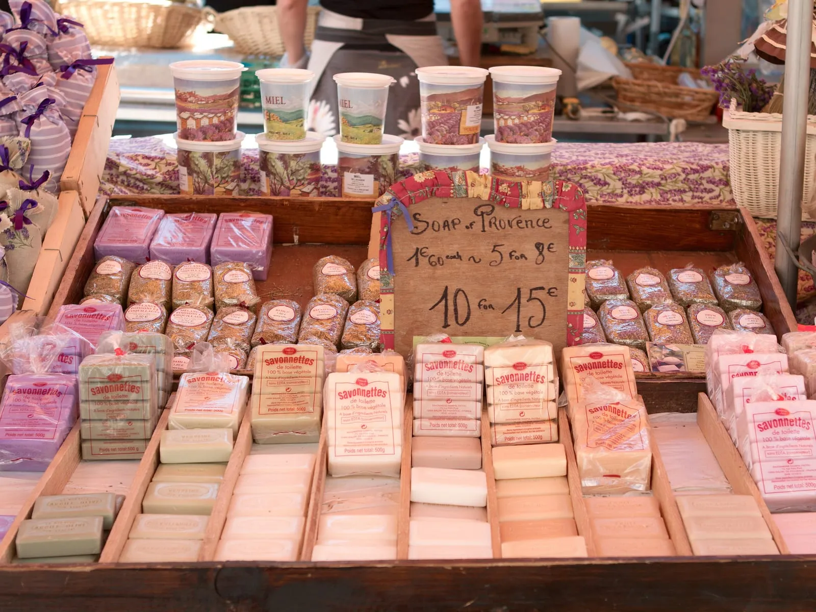 A market stall in Provence stacked with handmade soap bars under a hand-written price sign.
