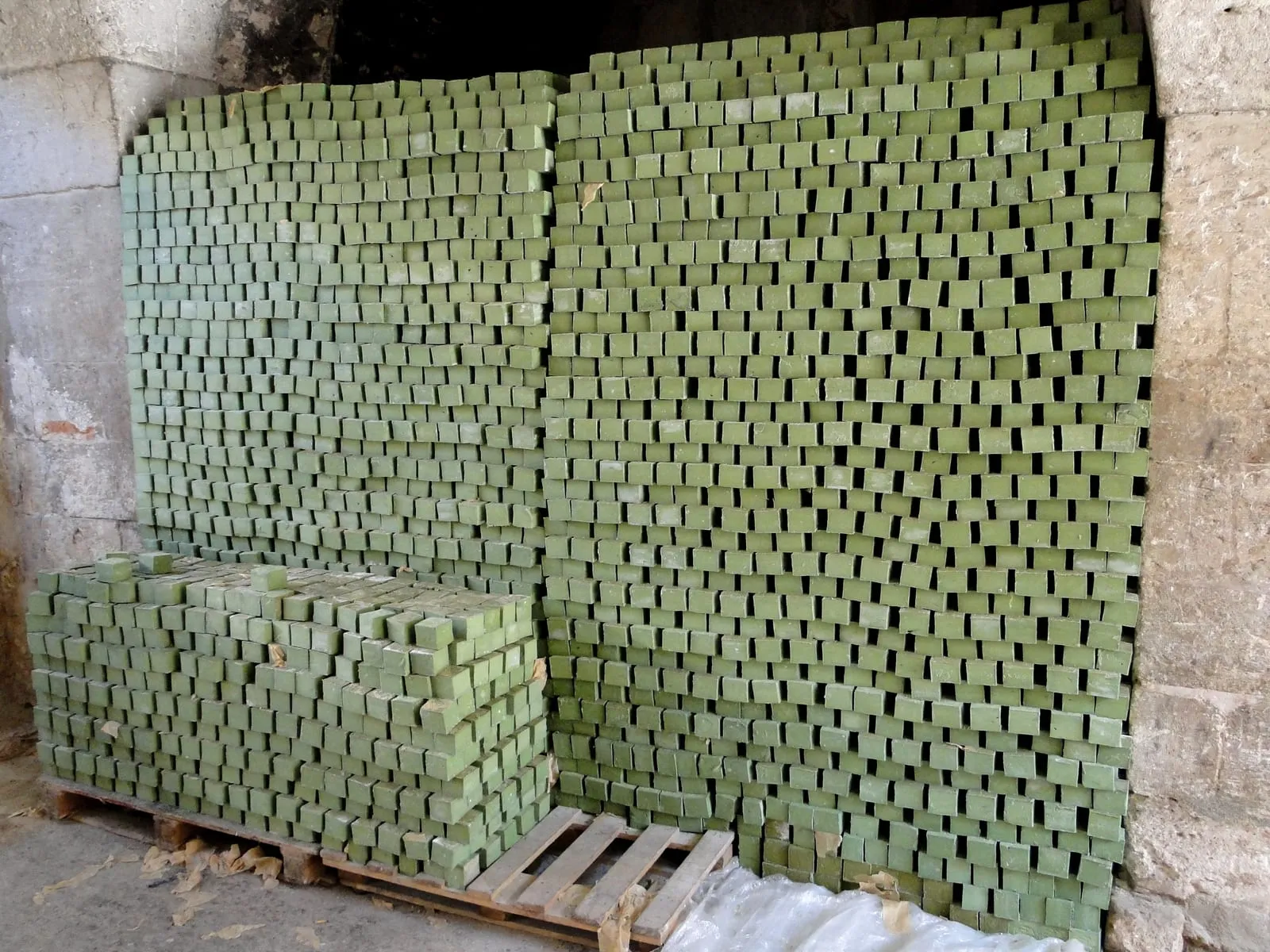 Thousands of green olive oil soap bars stacked in tall open towers to cure.