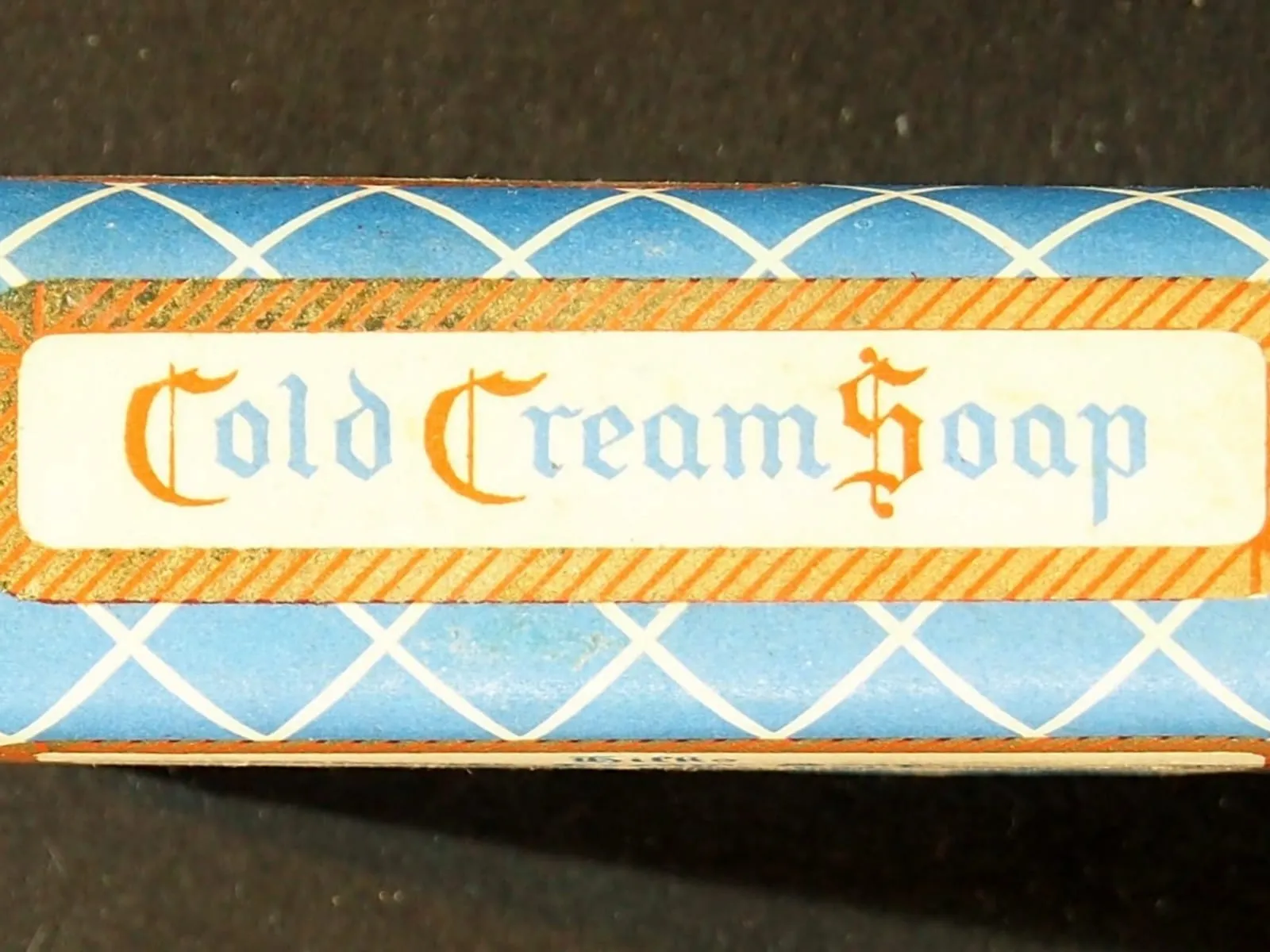A vintage paper-wrapped soap bar with a blue lattice wrapper and a label reading Cold Cream Soap.