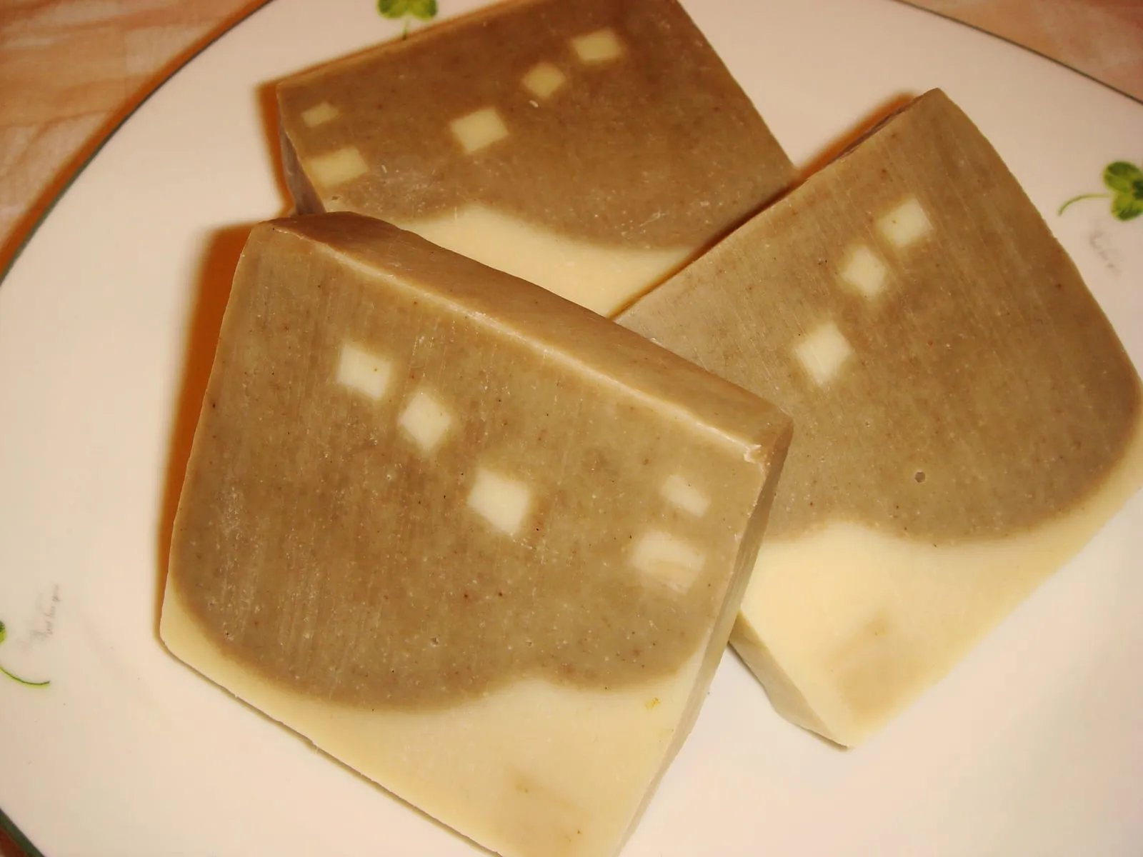 Three slices of handmade soap, two-toned brown and cream, with small square inlays.